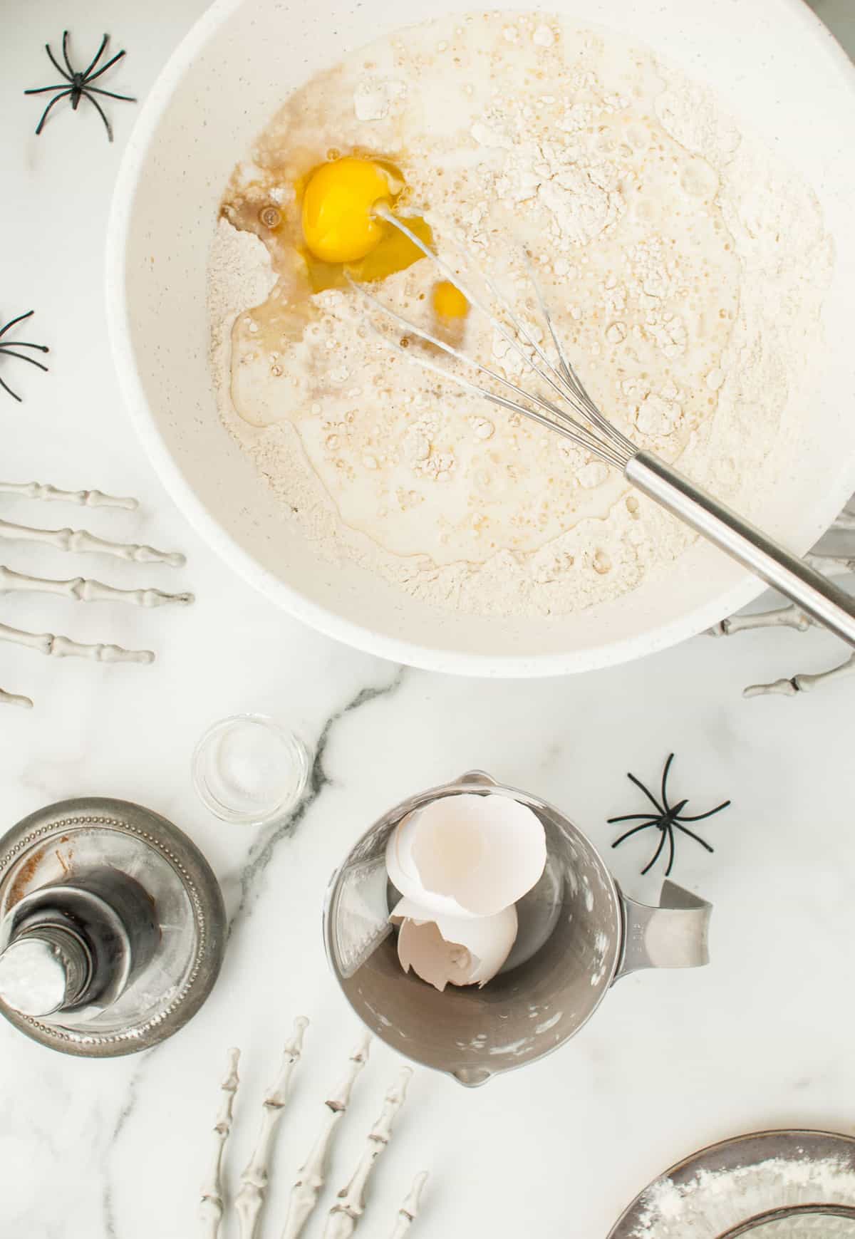 Dry pancake ingredients in a white mixing bowl with eggs and milk added.