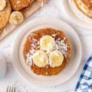 Overhead view of stack of pancakes topped with bananas and coconut.