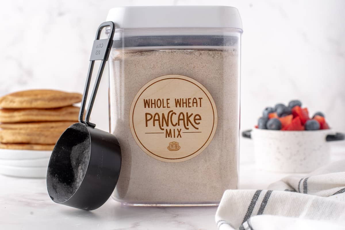 Pancake mix in a canister with a scoop next to it.