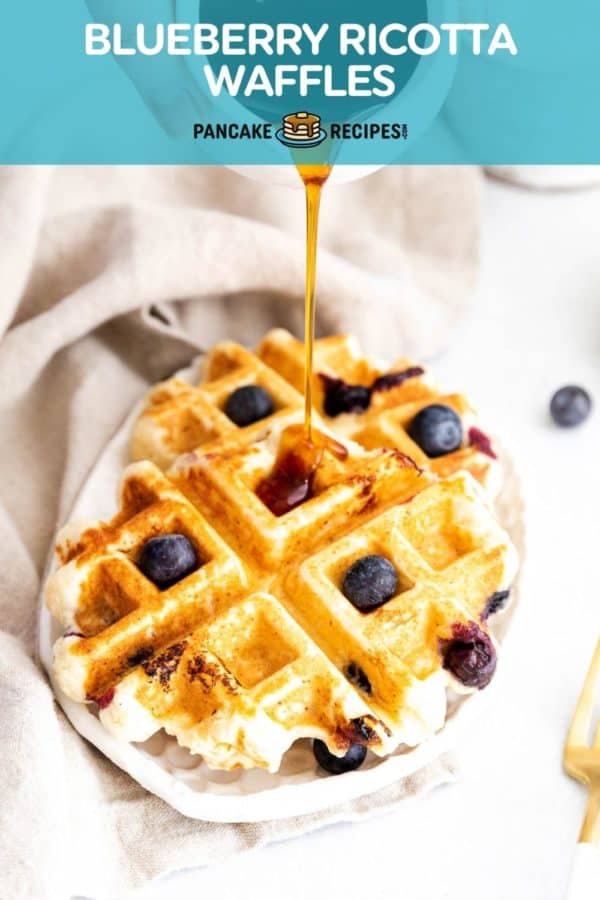 Waffles with blueberries with syrup being poured onto them. Text overlay reads "blueberry ricotta waffles."