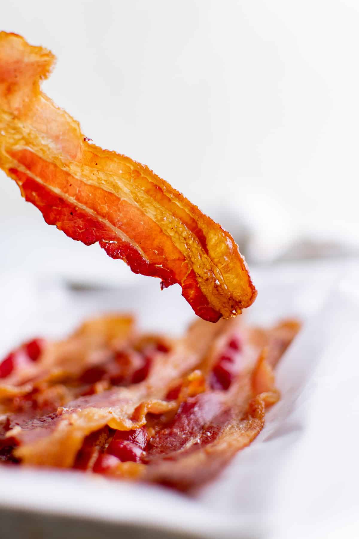 Piece of crispy bacon being held to show texture.