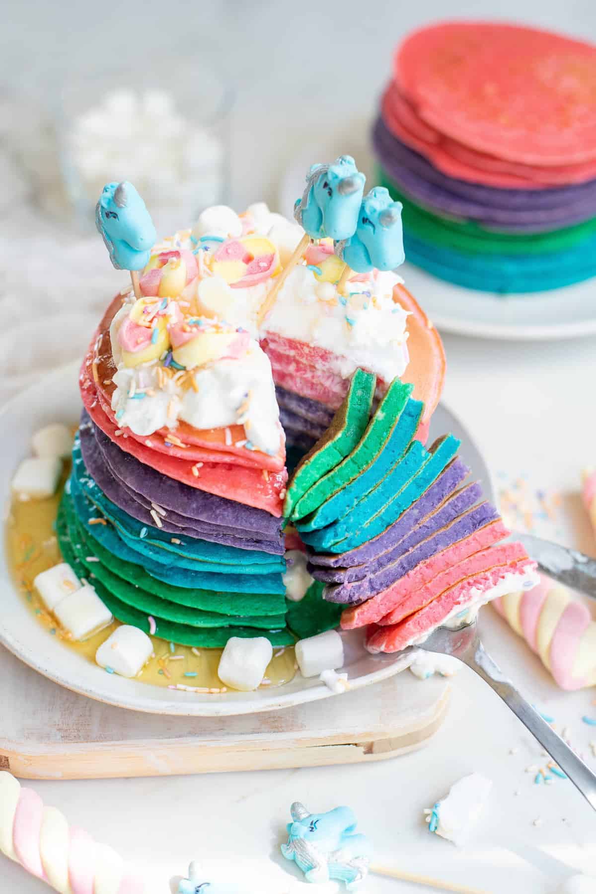 Unicorn pancakes with a slice cut out to show colors.