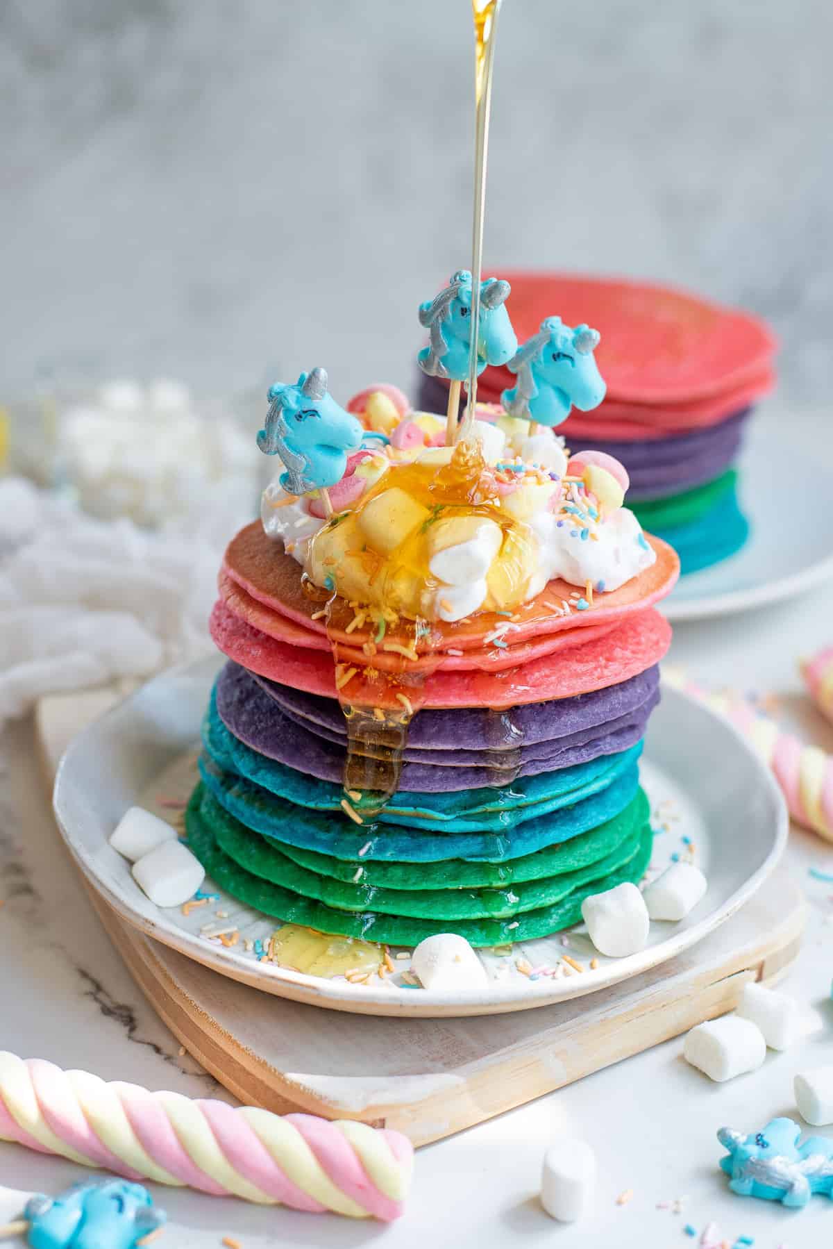 Stack of unicorn pancakes with honey drizzled on them.