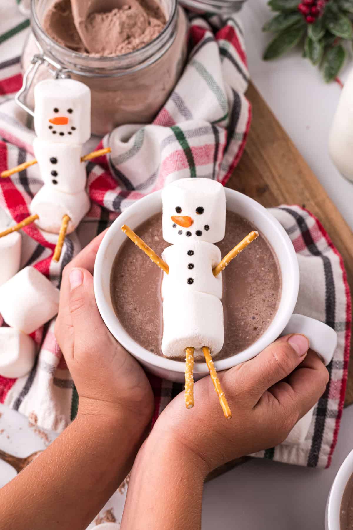 Marshmallow snowmen, one on top of a cup of hot cocoa.