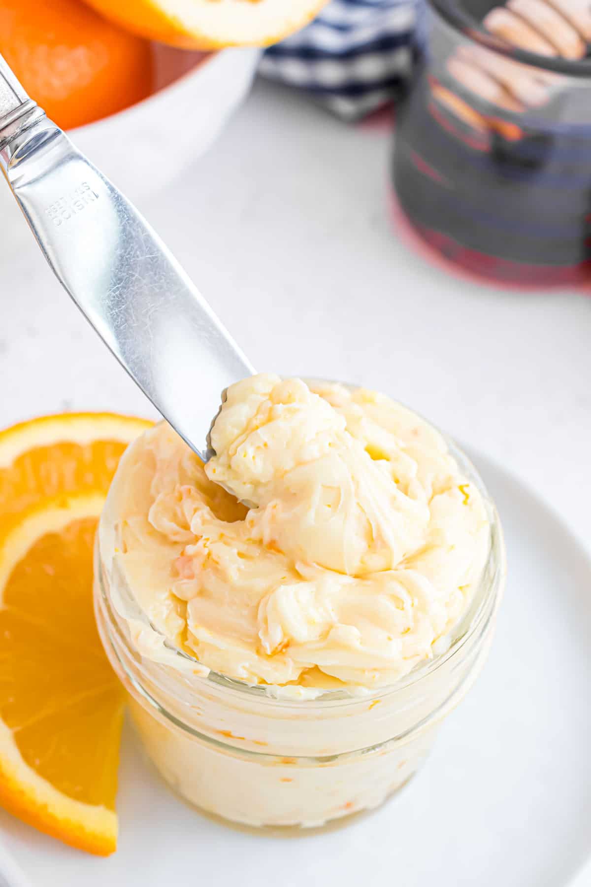 Orange honey butter on a knife and in a small jar.