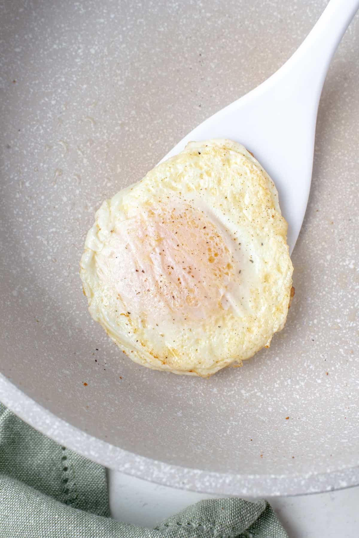 Egg being flipped with white spatula.