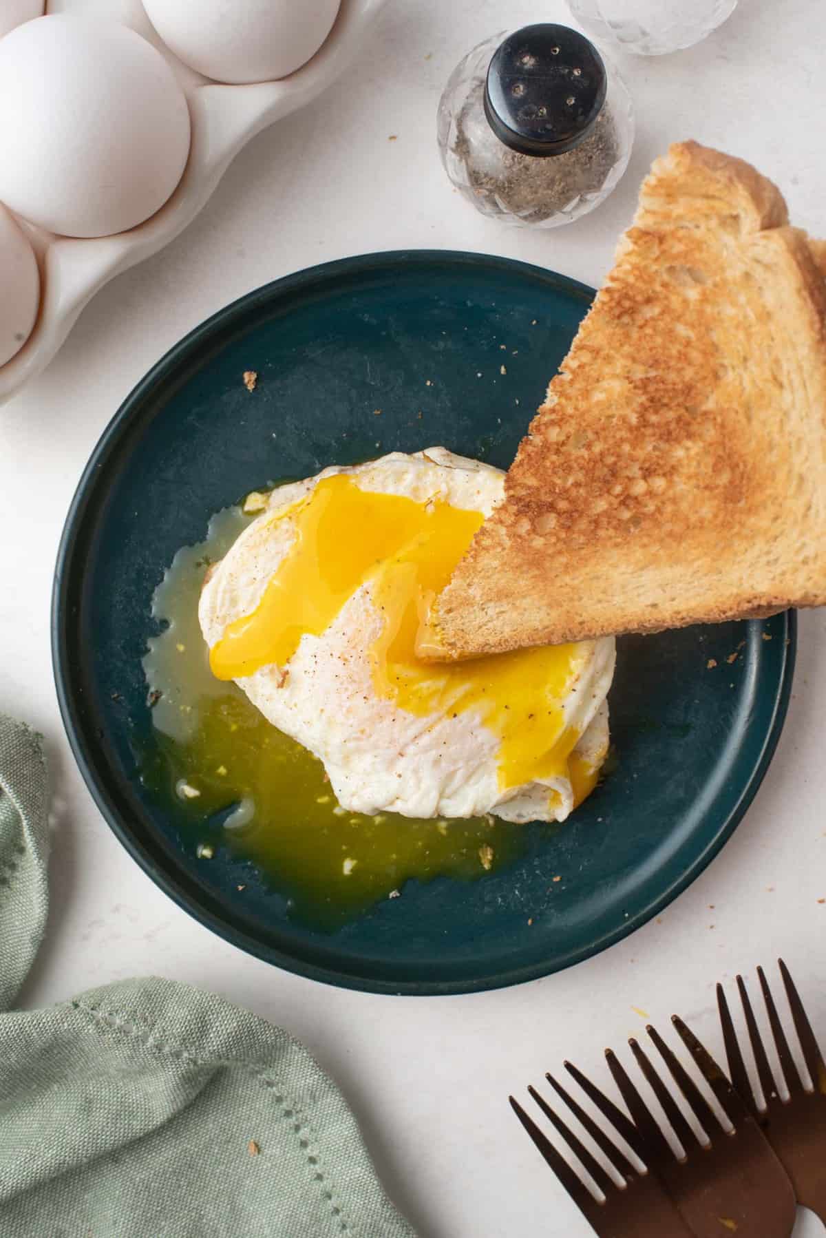 Triangle of toast being dipped in a runny egg.