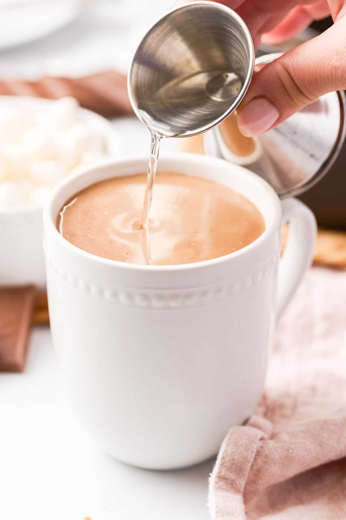 Liqueur being poured into a mug of cocoa.