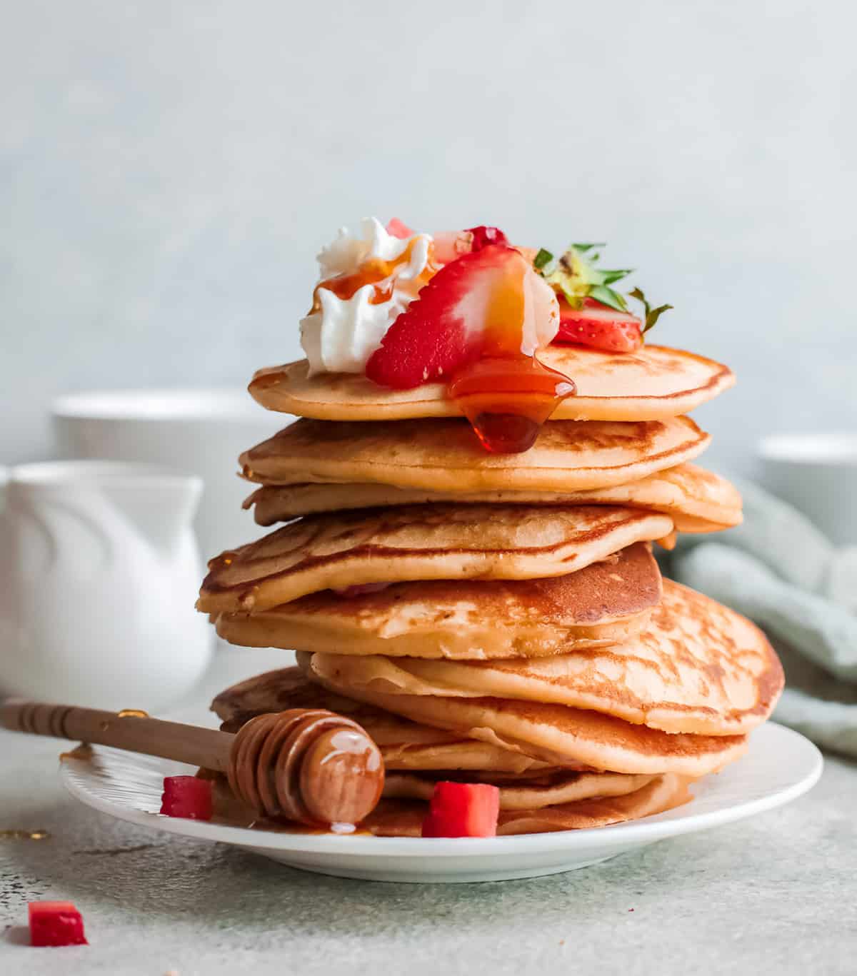 Very tall stack of strawberry ricotta pancakes topped with fresh strawberries.