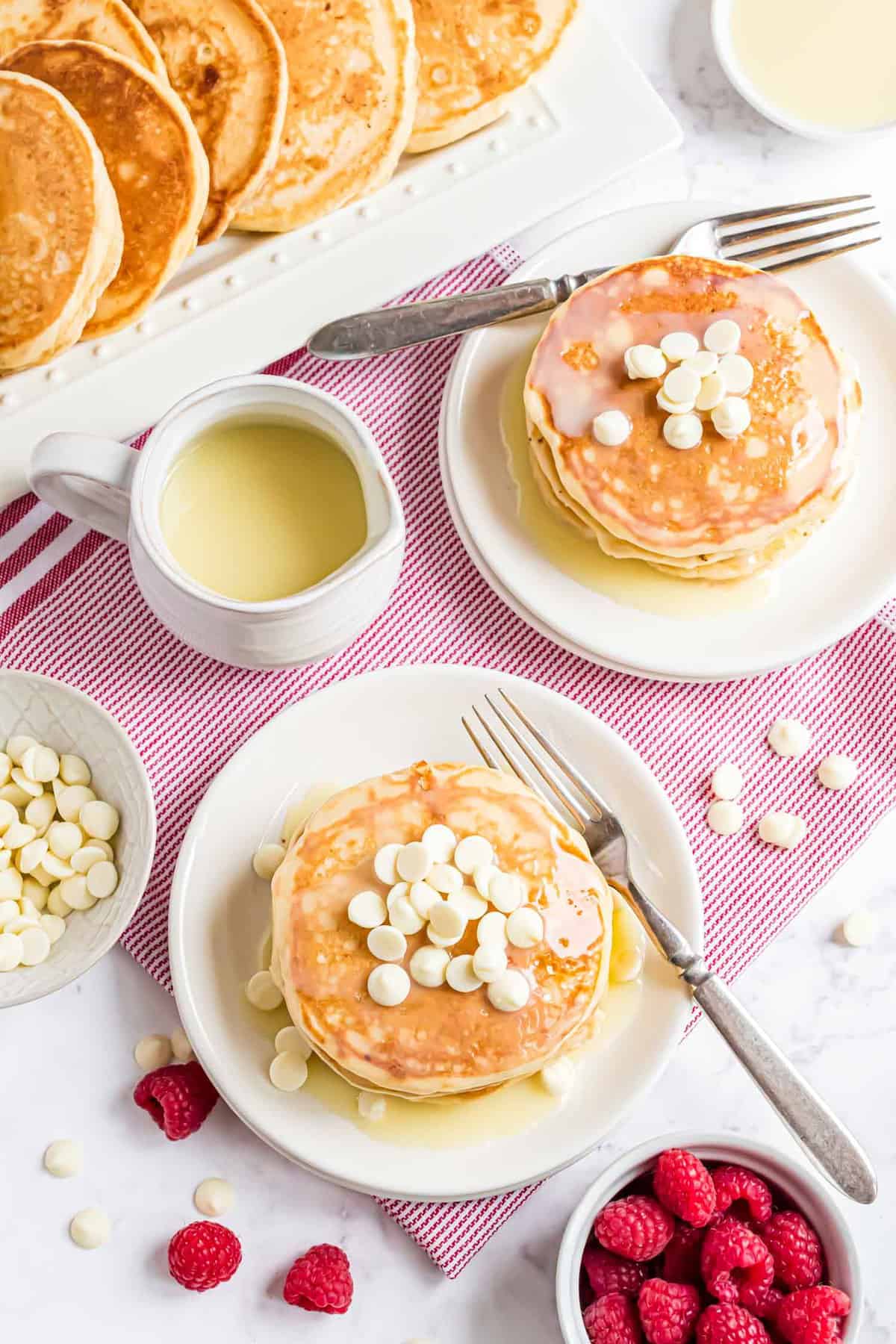 Overhead view of white chocolate pancakes with raspberries.