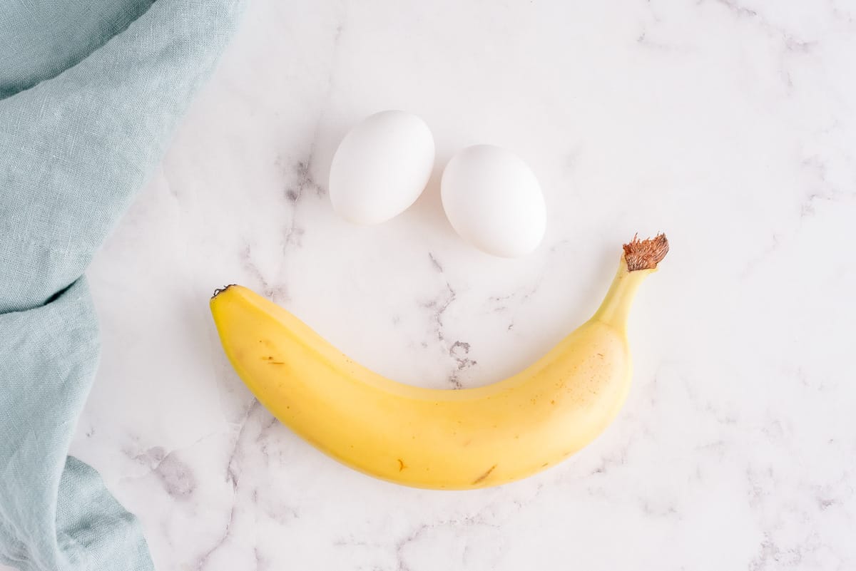 Two eggs and a banana on a marble background.