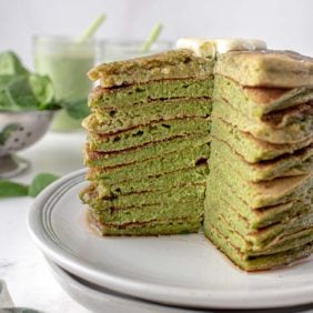 Stack of green pancakes with a wedge cut out to show color and texture.
