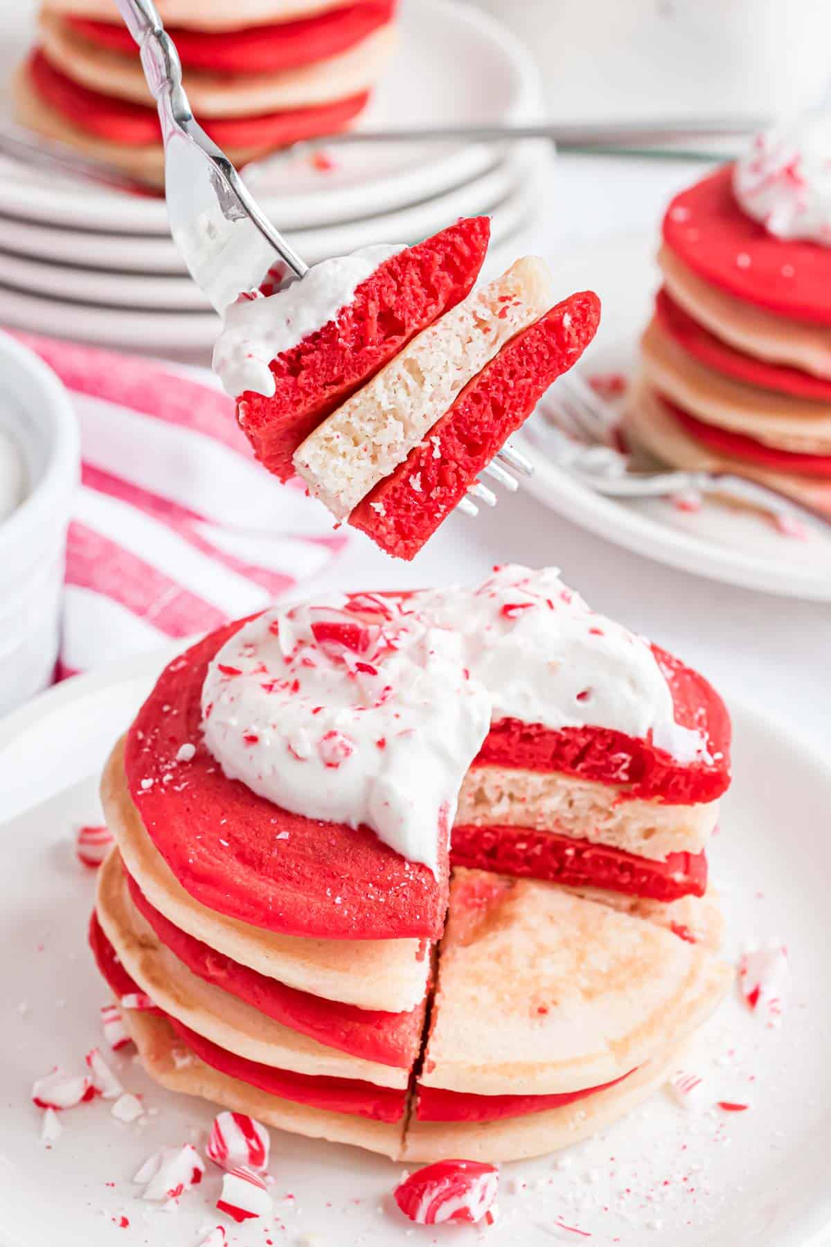 Red and white pancakes on a fork to show fluffy texture.