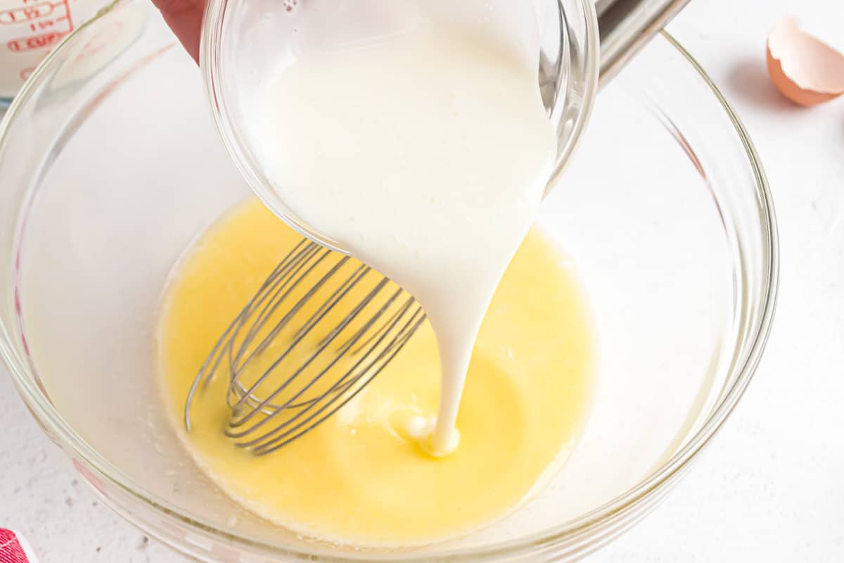 Milk being poured into eggs.