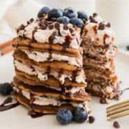 Stack of pancakes layered with ricotta cream filling topped with chocolate chips.