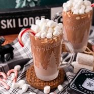 Peppermint hot chocolate garnished with marshmallows and a candy cane.