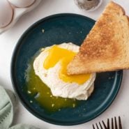 Toast being dipped into over easy egg.