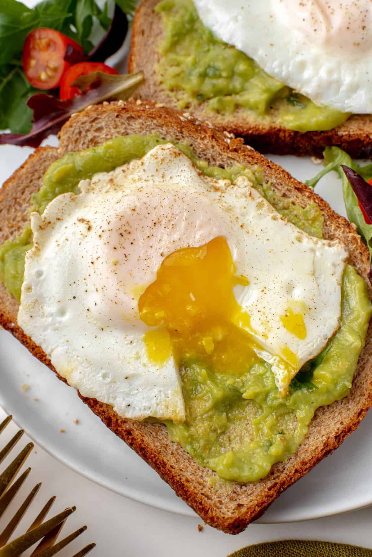 Egg with broken egg yolk on avocado toast.
