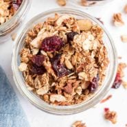 Overhead view of granola recipe with dried cranberries in a small glass jar.