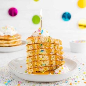 Wedge of pancakes with a candle on top.