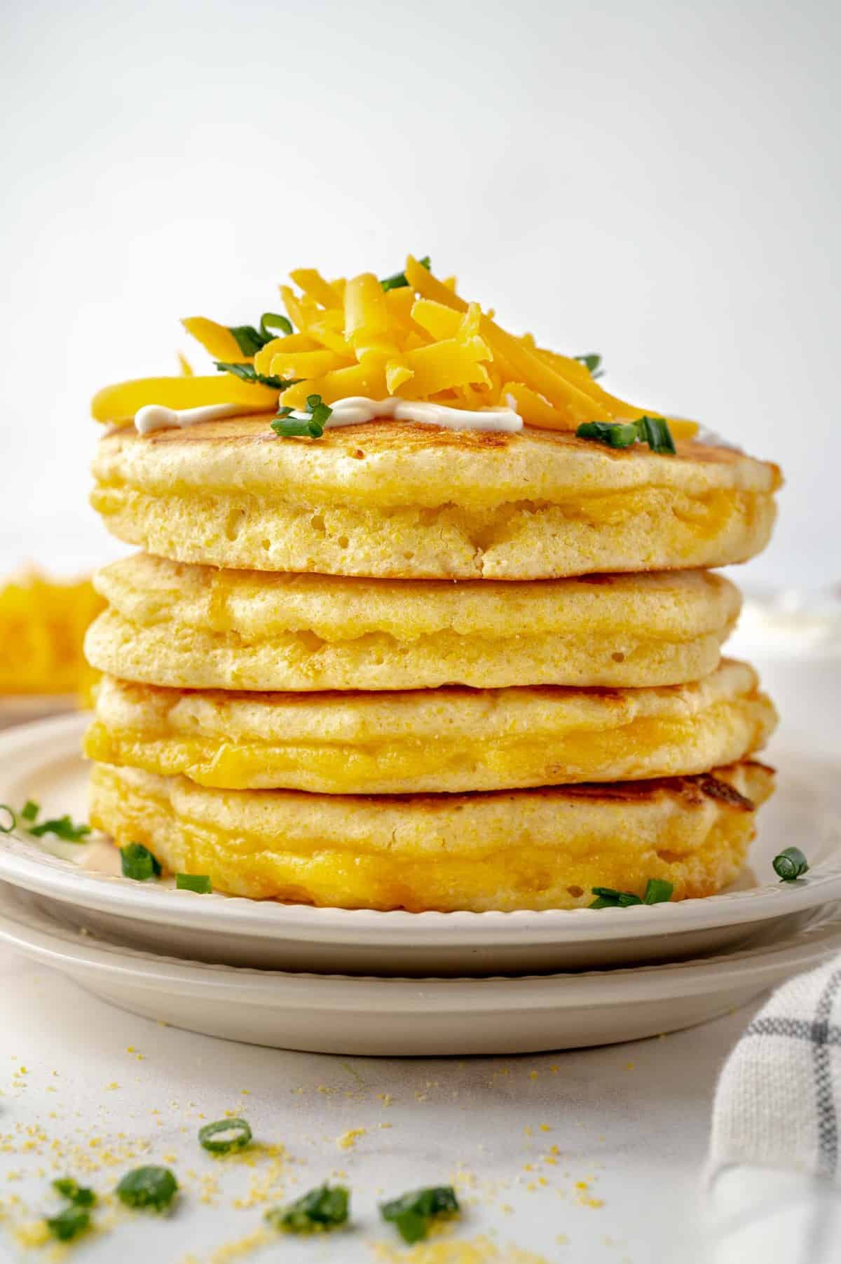 Stacked pancakes, topped with cheese and chives.