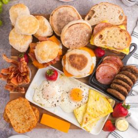 Breads, biscuits, eggs, meats, and more arranged on a board.