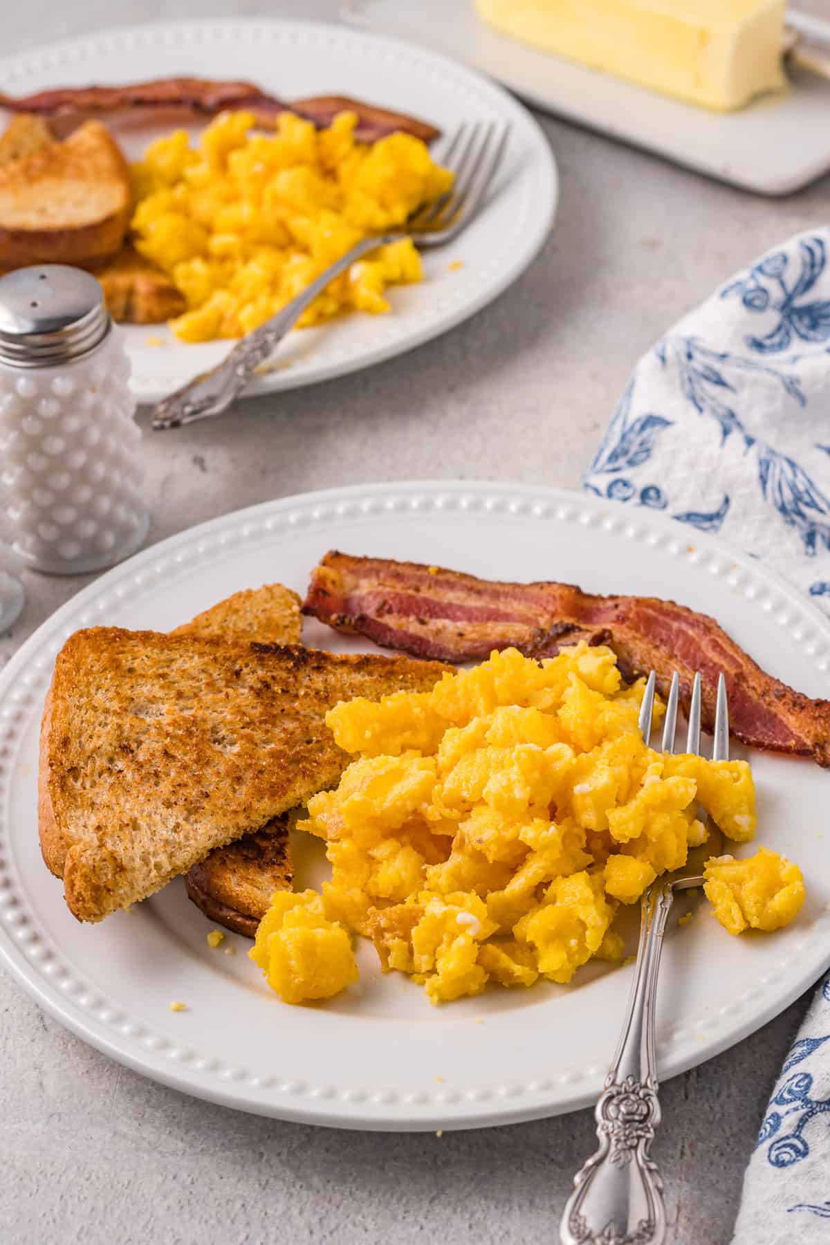 Air fryer scrambled eggs on a plate with bacon and toast.