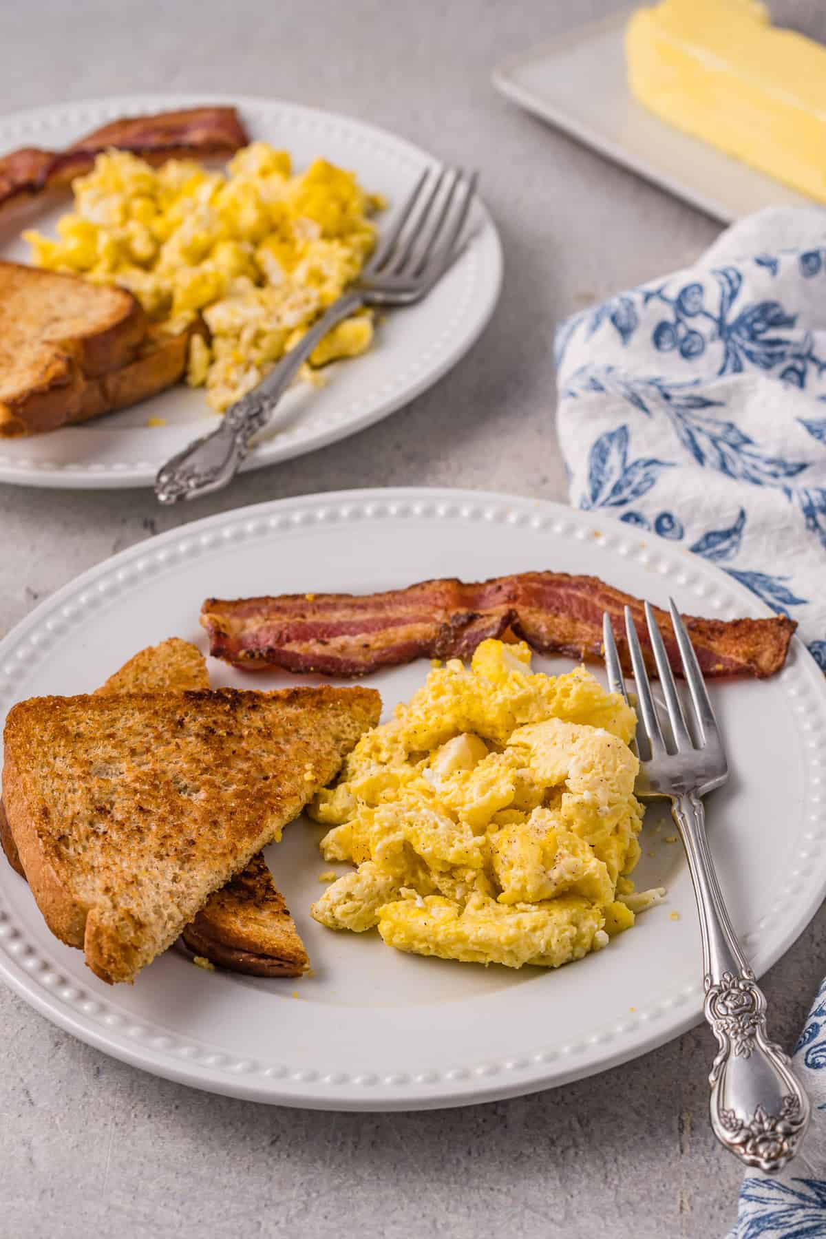 Scrambled eggs on a plate with bacon and toast.