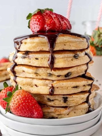 Stack of strawberry chocolate chip pancakes with chocolate syrup.
