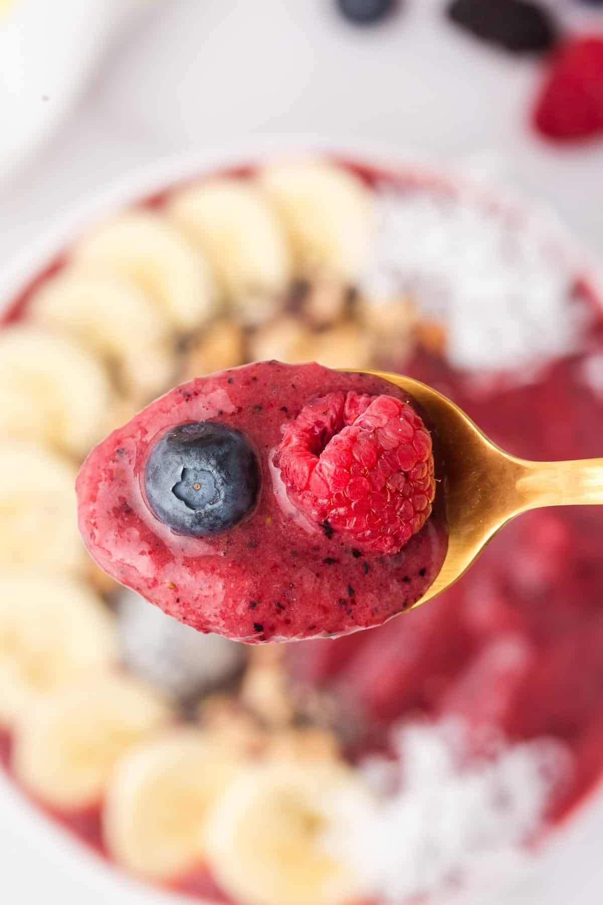 Smoothie and fresh berries on a spoon.