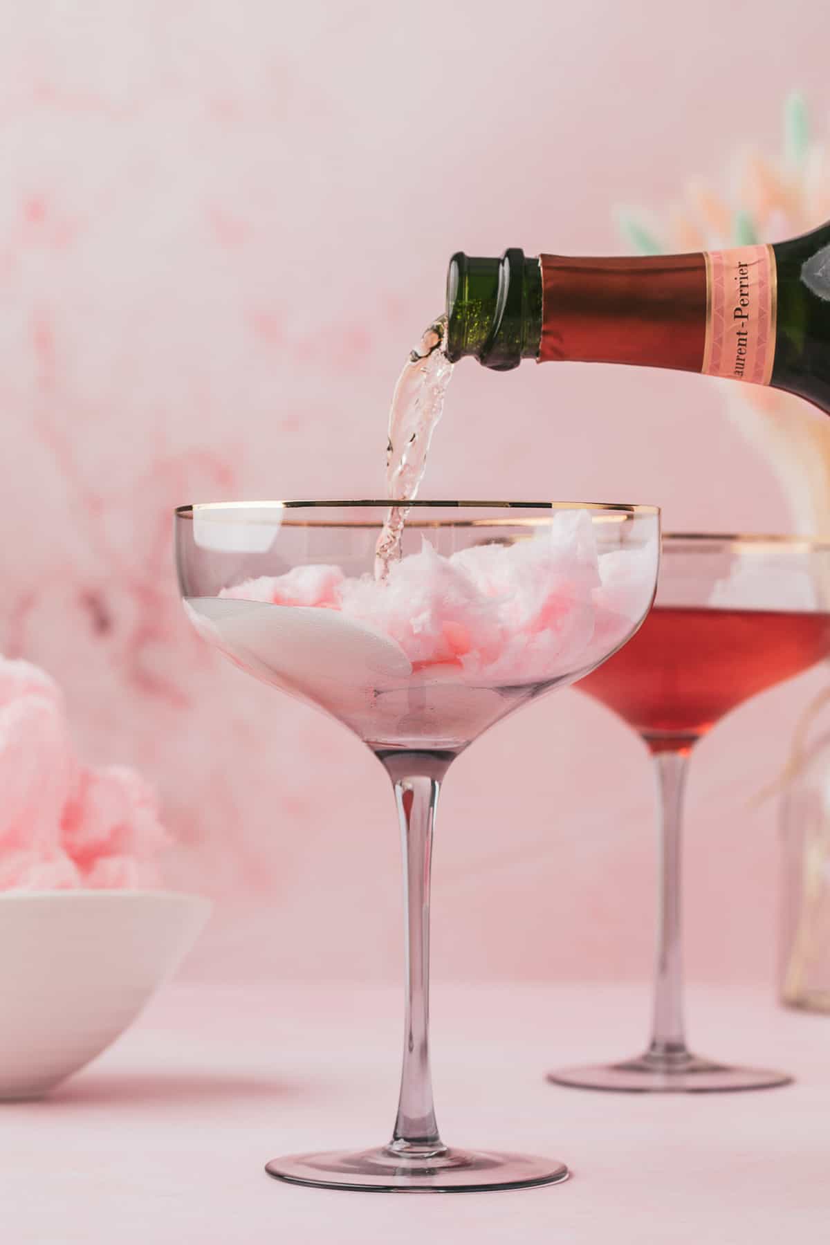Champagne being poured over cotton candy in a glass.