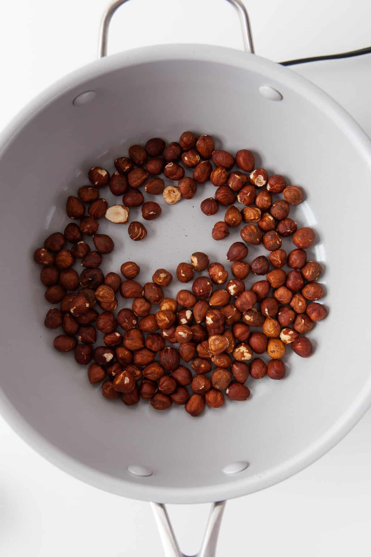 Toasted hazelnuts in a frying pan.