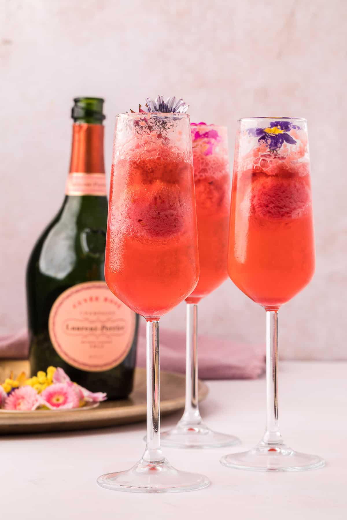 Three glasses of champagne floats with edible flowers.