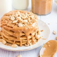Stack of peanut butter pancakes with peanut butter and peanuts.