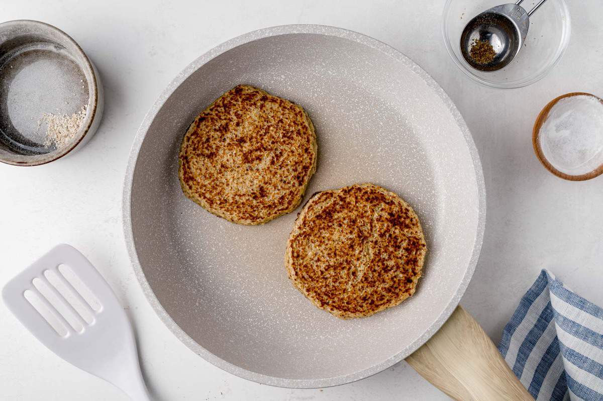 Honey oat pancakes on a white frying pan.
