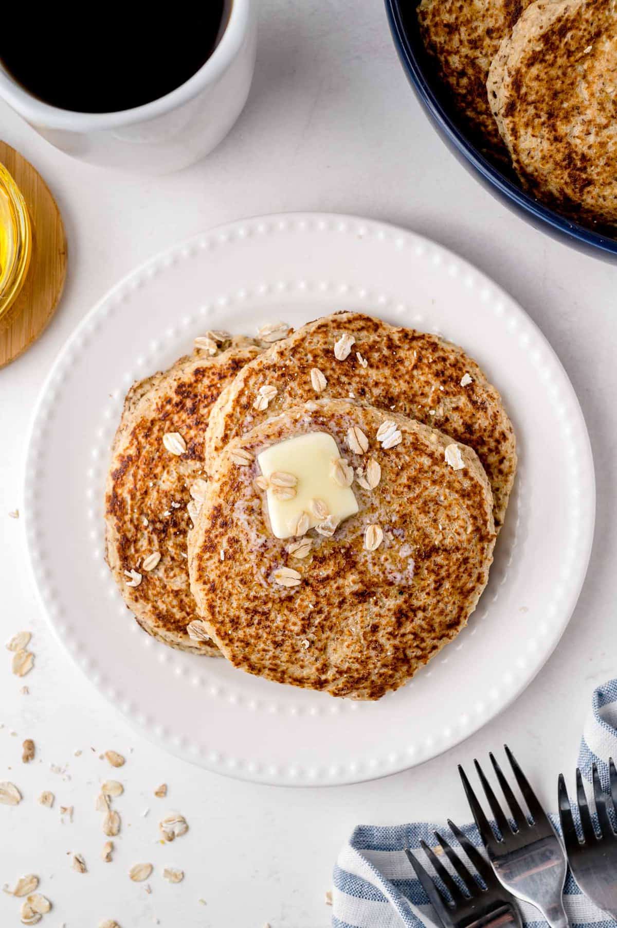 Three pancakes topped with butter and oats.