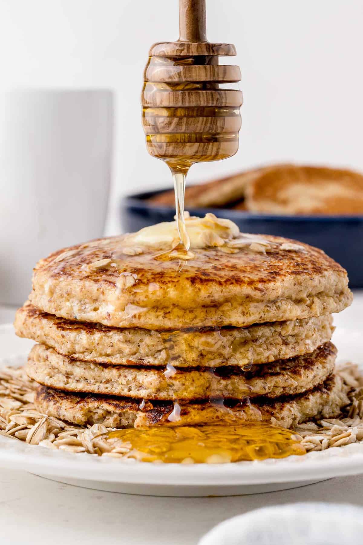 Honey being drizzled on honey oat pancakes.