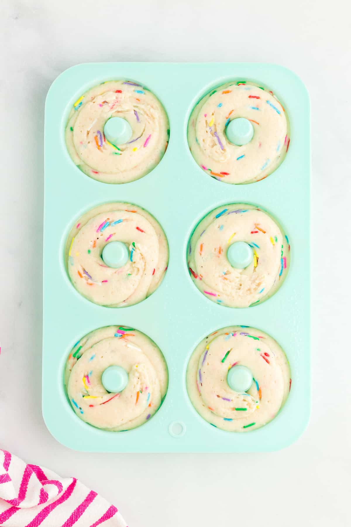 Unbaked donuts in blue silicone pan.