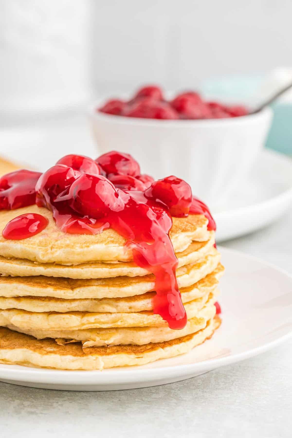 Stack of cherry pie pancakes with cherries on top.