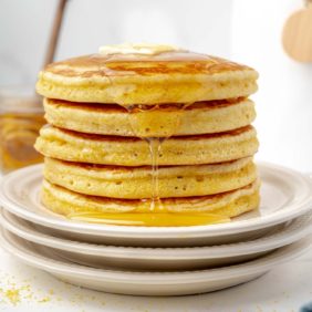 Stack of cornbread pancakes drizzled with honey.