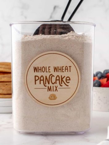 Labeled canister with whole wheat pancake mix and a scoop.