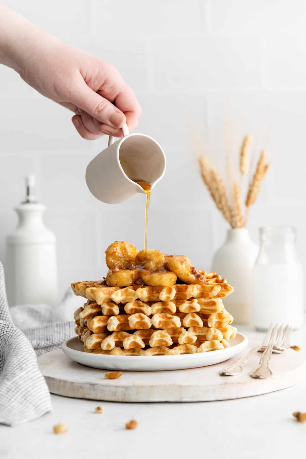 Bananas foster waffles with syrup being poured on.