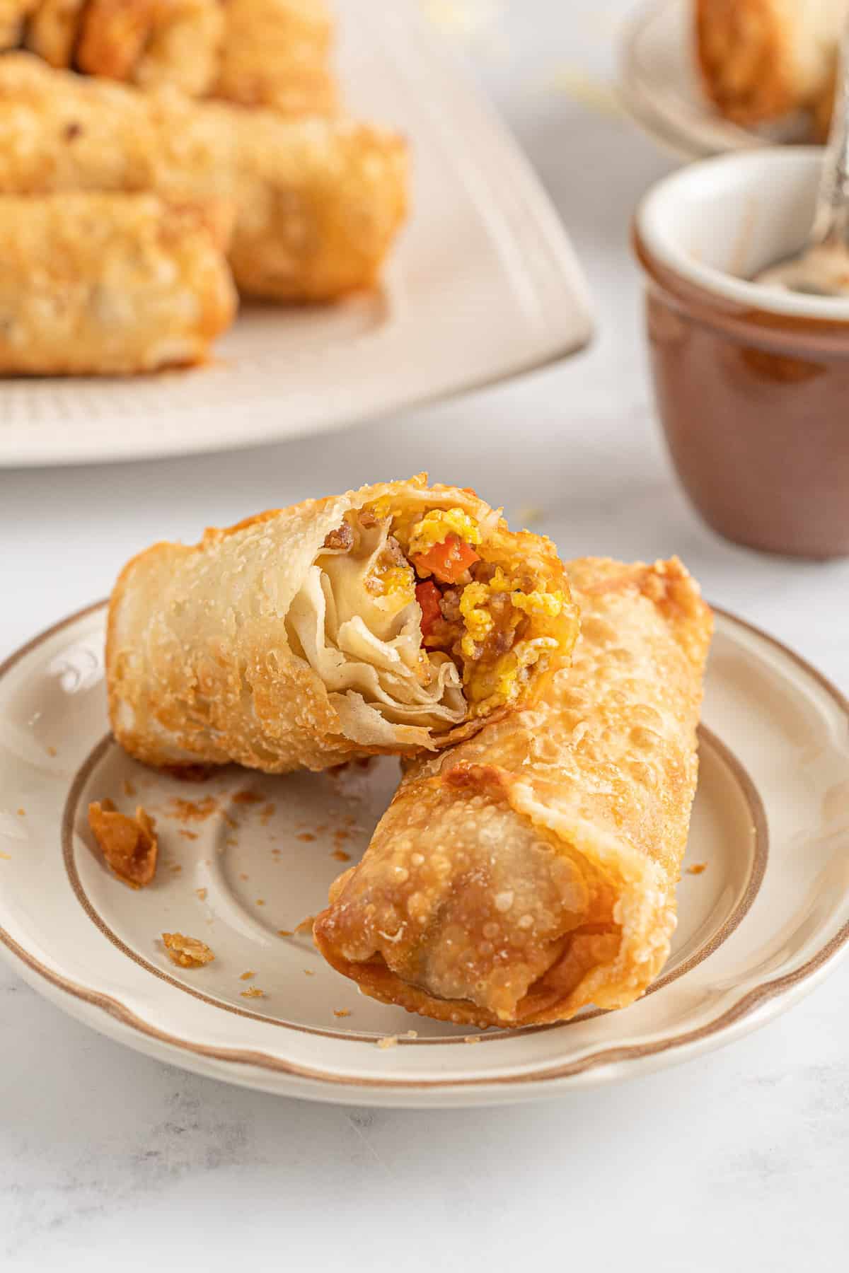 Two breakfast egg rolls, one cut to show texture.