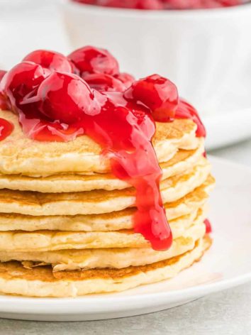 Cherry pie pancakes stacked with cherries on top.