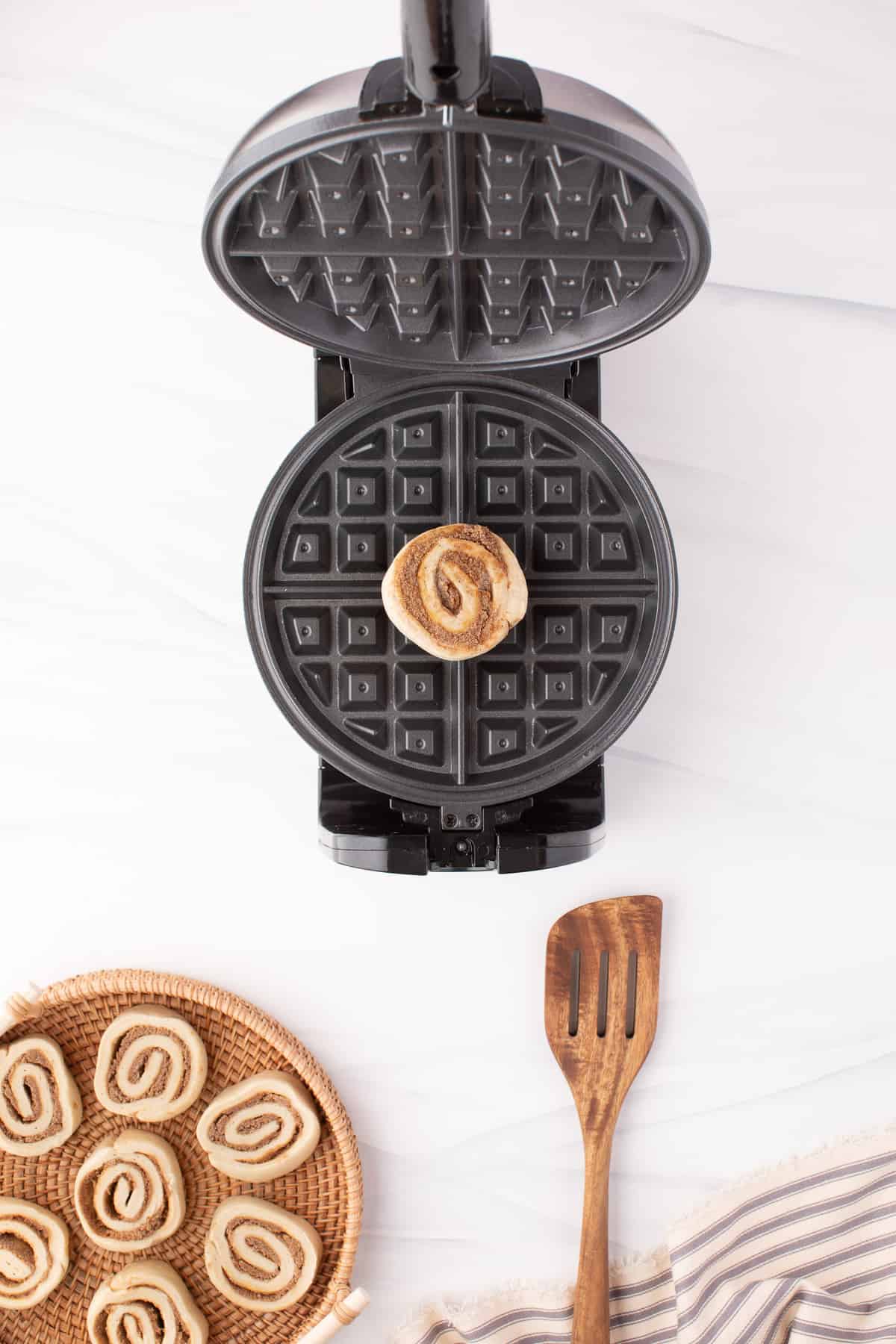 Uncooked cinnamon roll in a waffle maker.