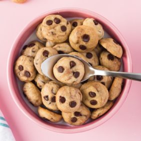 Tiny cookies making up cookie cereal in a pink bowl with milk.