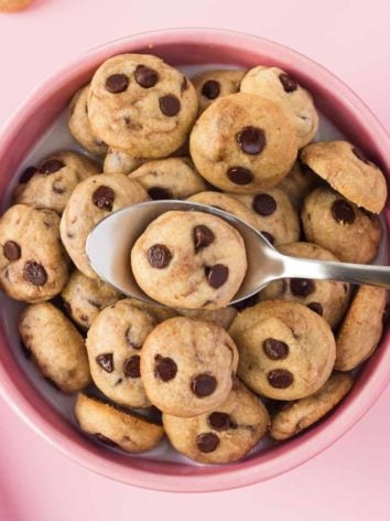 Tiny cookies making up cookie cereal in a pink bowl with milk.