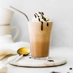 Mocha Frappuccino in a clear glass with whipped cream and chocolate syrup.