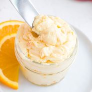 Orange honey butter in a small jar and on a knife.