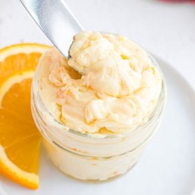 Orange honey butter in a small jar and on a knife.